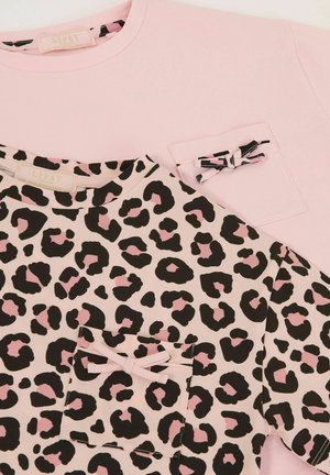 Dva T-shirta: jedan jednobojni ružičasti s džepom, a drugi bež s crnim i ružičastim gepardovim mrljama. Drugi ima naglasak u obliku mašne na džepu.