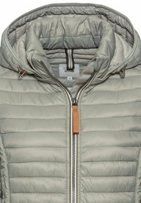 Veste matelassée grise avec capuche. Présente une texture matelassée, une fermeture éclair à l'avant et une étiquette en cuir. L'intérieur montre une doublure rayée.