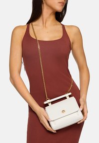 Borsa bianca con design strutturato, hardware dorato e tracolla a catena. Realizzata in materiale liscio, presenta un manico superiore e una chiusura a pattina.