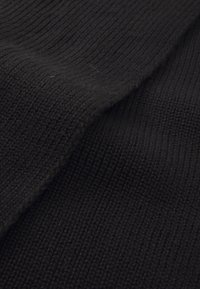 Tissu tricoté noir avec une texture côtelée, présentant une finition douce et des variations subtiles d'épaisseur.