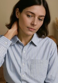 Lichtblauwe button-up shirt met witte verticale strepen, voorzien van een borstzak en klassiek kraag. Glad stof met standaard manchetten.