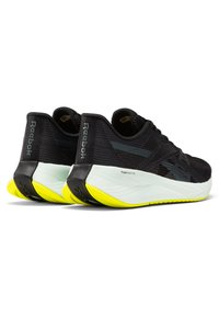 Baskets de sport noires avec une tige texturée, une semelle intermédiaire blanche proéminente et une semelle extérieure jaune fluo. Présente la marque "FLOATRIDE FUEL" sur le côté.