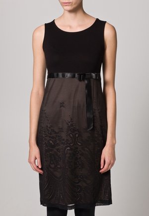 Robe noire sans manches avec un haut ajusté, une partie inférieure en dentelle fluide et une ceinture en satin à la taille. Motif floral complexe sur la dentelle.