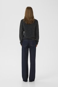 Pull en tricot gris foncé et un jean en denim bleu foncé à coupe ample. Le pull a un col rond ; le jean présente des poches arrière et des jambes droites.