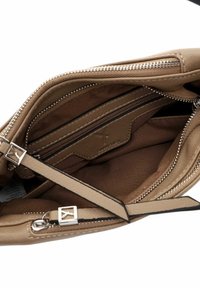 Interno della borsa in pelle marrone con scomparti con zip e una morbida fodera in tessuto. Presenta accessori in argento e una tracolla sottile e regolabile.