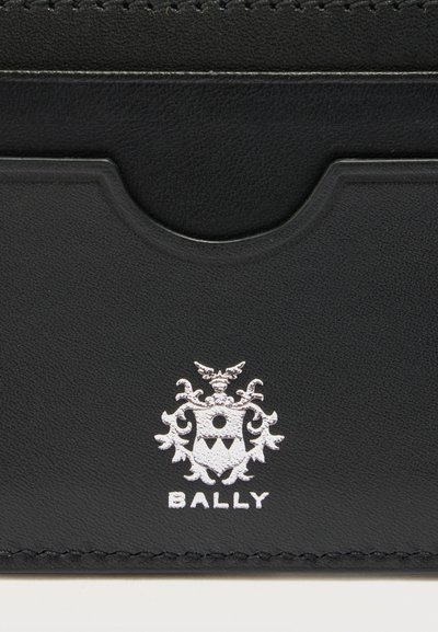Porte-cartes en cuir noir avec une poche centrale et le logo blanc de Bally présentant un blason avec des éléments décoratifs.