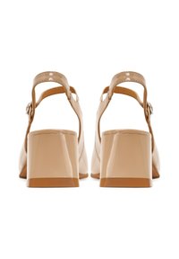 Tacchi in pelle patent color beige con tacco a blocco, cinturino alla caviglia regolabile e superficie liscia. Presentano un design con apertura arrotondata sul retro.