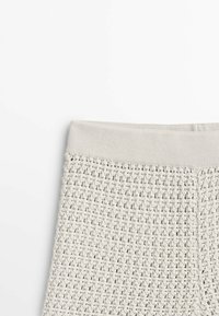 Light grey knitted leggings featuring a textured pattern and a smooth waistband. Made from flexible material for comfort and fit.