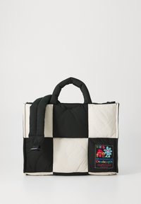 Geantă tote quilted în negru și crem, cu mânere căptușite și un patch cu text brodat și desene colorate pe o parte.