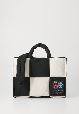Sac fourre-tout matelassé noir et crème avec des poignées rembourrées et un patch présentant un texte brodé et des designs colorés d'un côté.