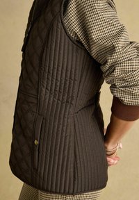 Kvadru gaisma brūna veste ar dimanta rakstu, ar sānu kabatu un gludu faktūru. Valkāta virs suni rīkota apģērba.