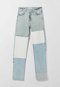 Jeans de denim con un diseño de patchwork en tonos azul claro y blanco. La tela tiene una textura desgastada con bordes sin rematar y un corte de pierna recta.