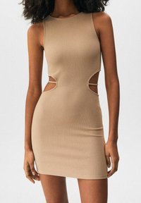 Vestido de canalé beige con detalles recortados en los laterales, diseño sin mangas, silueta ajustada y largo hasta la rodilla. Textura suave y estilo minimalista.