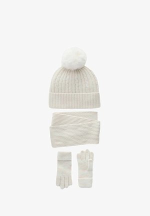 Fehér kötött téli sapka pom-pommal, hozzáillő bordázott sál és ujjatlan kesztyű, mindegyik puha, texturált anyagból készült.
