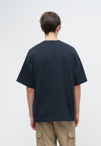 Námorně modré oversized bavlněné tričko s krátkým rukávem a kulatým výstřihem, s minimálním šitím a hladkým povrchem.