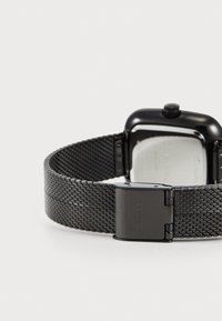 Bracelet de montre en maille en acier inoxydable noir avec une finition mate. Présente un boîtier rectangulaire noir et une fermeture à clip. Fond de boîtier transparent visible.