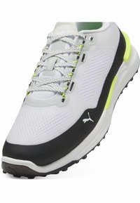 Bele golf čevlje z mrežastim zgornjim delom, črnim podplatom in rumenimi poudarki. Imajo strukturirano obliko in kontrastne vezalke za varen oprijem.