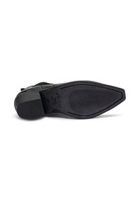 Zapato de cuero negro con una suela de goma texturizada. Presenta una punta afilada y detalles de costura a lo largo del borde. Diseño de suela plana.