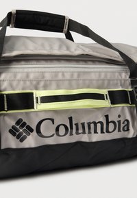 Τσάντα τύπου duffel Columbia σε γκρι και μαύρο ύφασμα, με ρυθμιζόμενα μαύρα λουριά μεταφοράς, κίτρινες λεπτομέρειες και εμφανές λογότυπο στο πλάι.