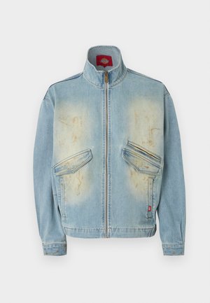Giacca di jeans azzurro chiaro con collo alto, zip frontale, due tasche con patta e toppe sbiadite e consumate sul petto e sui polsini.