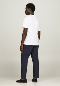 T-shirt bianca in cotone con colletto rotondo, abbinata a pantaloni blu navy e mocassini blu scuro. Design semplice e vestibilità rilassata.