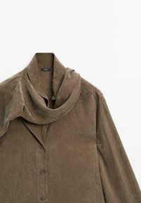 Brun ruskind bluse med lange ærmer, knapper ned foran og et tilhørende matchende tørklæde draperet omkring kraven.