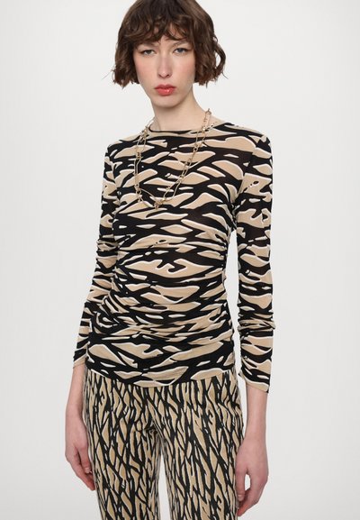 Long-sleeve shirt with a black and beige abstract pattern, made from a soft fabric, paired with matching patterned pants and gold chain necklace.