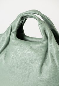 Borsa a mano in pelle verde testurizzata con manici arrotondati e il logo "aunts & uncles" impresso in modo discreto sulla parte anteriore.