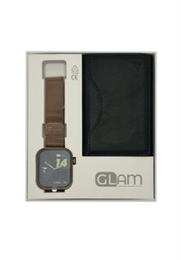 Montre intelligente dans une boîte avec un bracelet en maille métallique bronze ; le cadran carré affiche l'heure numérique en vert ; inclut un portefeuille en cuir noir.