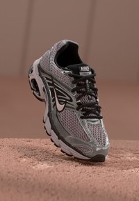 Nike running shoe in gray and pink mesh with black accents, featuring a lace-up design and cushioned sole for support.
