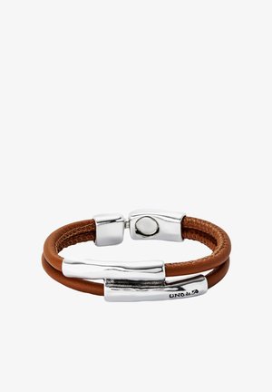 Pulsera de cuero en color marrón, con herrajes plateados de acabado texturizado. El diseño incluye dos correas entrelazadas y un cierre magnético.