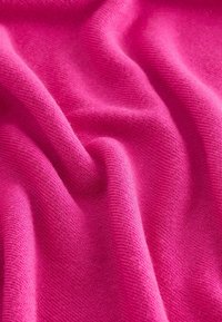 Tissu doux et texturé d'un rose vibrant, présentant une surface lisse avec une légère élasticité et un tombé fluide, formant des ondulations et des plis délicats.