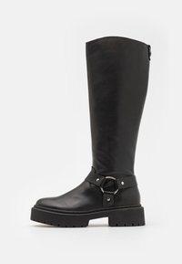 Bota de cuero negro hasta la rodilla con un acento de hebilla redonda. Presenta una suela resistente y un acabado texturizado, con una parte superior suave y una correa ajustable.