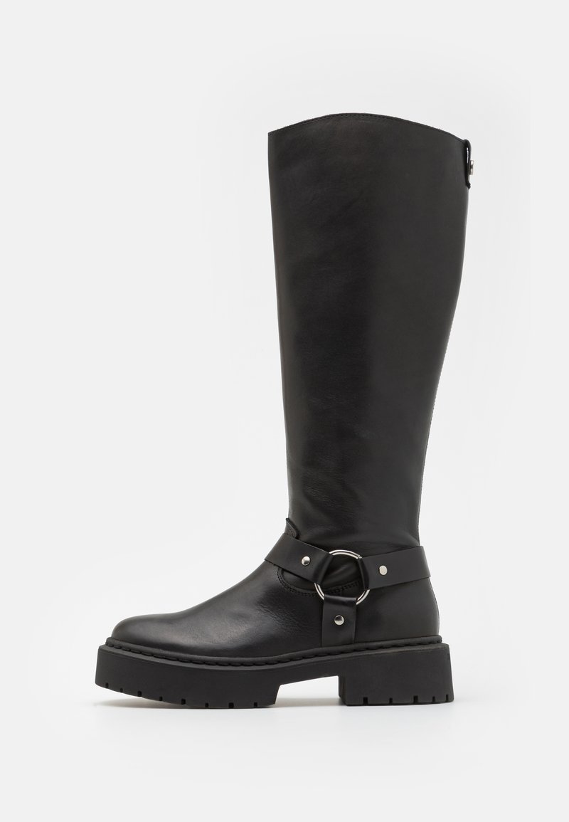 Bota de cuero negro hasta la rodilla con un acento de hebilla redonda. Presenta una suela resistente y un acabado texturizado, con una parte superior suave y una correa ajustable.