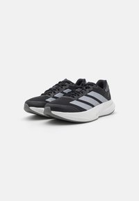 Schwarze Sportschuhe mit einem Obermaterial aus Mesh, ausgestattet mit drei grauen seitlichen Streifen, einer gepolsterten weißen Zwischensohle und einer Gummisohle.