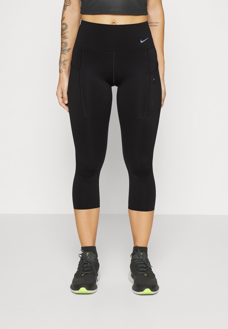 Leggings noirs coupés avec une taille haute, dotés de deux poches latérales et d'un logo Nike bleu subtil. Tissu lisse et extensible.
