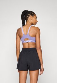 Lilla sports-bh med utskjæringsdetaljer og justerbare stropper, sammen med svarte treningsshorts med elastisk liv.