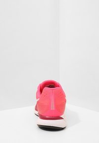Scarpe da corsa con tomaia rosa brillante, tessuto a rete traspirante, tallone texturizzato e una suola intermedia bianca imbottita. Presentano un logo riflettente.
