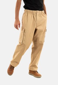 Beige cargobroek met een elastische tailleband, uitgerust met zijzakken en een relaxed fit. Gemaakt van een lichtgewicht stof.