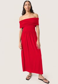Raudona maxi sukurta su petnešomis su susiraukšlėjusiu liemeniu ir laisvu sijonu. Pagaminta iš lengvo audinio, sukurta su patogiu elastingu juosmeniu.