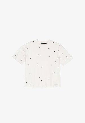 Biała bawełniana koszulka z luźnym krojem, z małymi czarnymi kropkami równomiernie rozmieszczonymi na całej powierzchni. Krótkie rękawy, okrągły dekolt.