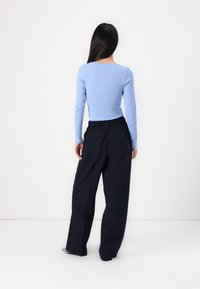 Haut bleu clair à manches longues avec un corsage ajusté associé à un pantalon large navy à taille élastique.