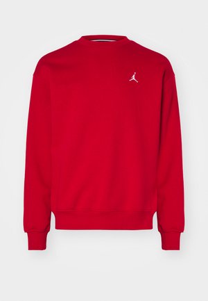 Sweat-shirt rouge avec col rond et manches longues. Présente un logo Jordan blanc sur la poitrine. Fabriqué à partir d'un tissu doux et texturé.