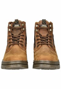 Botas de tobillo de cuero marrón con ojales de metal y cordones, que cuentan con una superficie texturizada, suela de goma y acentos oscuros en los laterales.