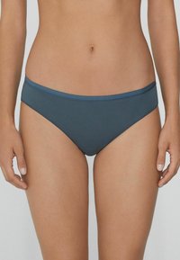 Bikini kalhotky se středním výstřihem v tlumené modrošedé barvě, vyrobené z hladké, pružné tkaniny s jednoduchým, čistým designem a kontrastním páskem.