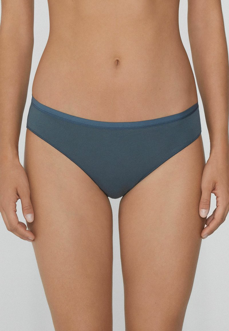 Bikini kalhotky se středním výstřihem v tlumené modrošedé barvě, vyrobené z hladké, pružné tkaniny s jednoduchým, čistým designem a kontrastním páskem.