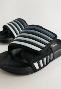 Sandale tip șlapi negre cu tălpi texturate, având o curea groasă cu dungi orizontale negre, gri și albe. Design simplu, culoare versatilă.