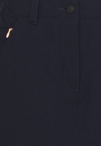 Ciemnogranatowe spodnie wykonane z gładkiego materiału, wyposażone w kieszeń na zamek z kontrastującym pomarańczowym suwakiem oraz dopasowaną talię z pętlami na pasek.