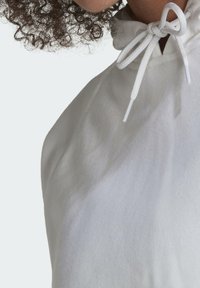 White hooded garment with a gathered neckline and adjustable drawstring, made of soft fabric, featuring a smooth texture and minimal design.