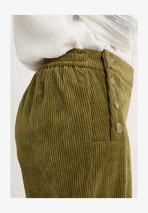 Pantalons en velours côtelé vert olive avec des côtes verticales, une taille élastique et trois boutons décoratifs à l'avant. Poche latérale visible.